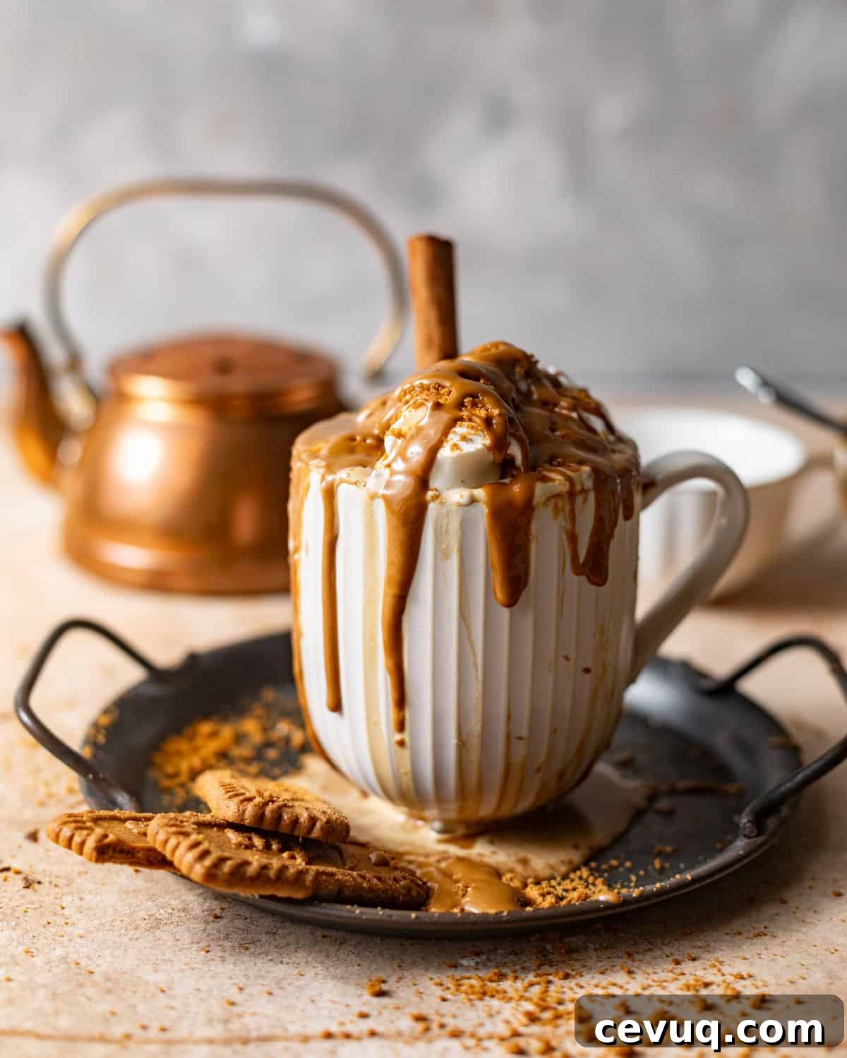 cookie butter latte on a plate with crushed biscoff cookies and melted cookie butter on top.