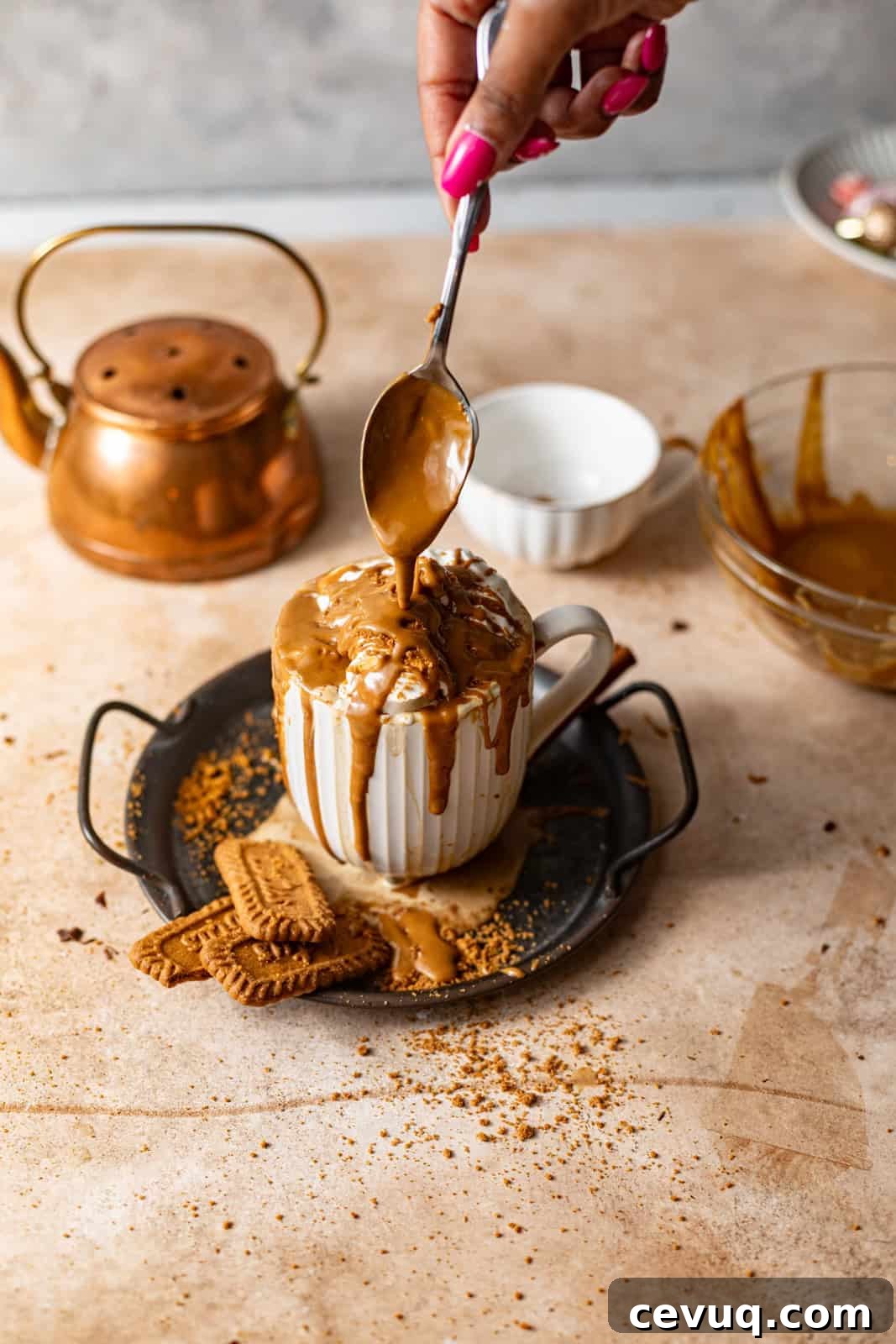 a spoon pouring melted cookie butter on top of the latte.