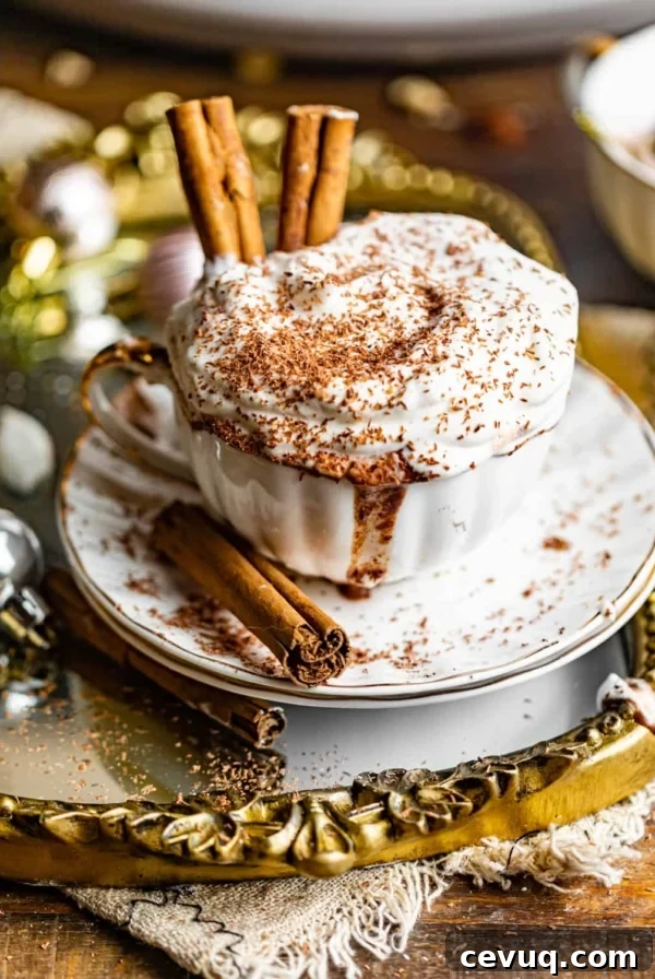 a cup of crock pot hot chocolate in a cup with cinnamon sticks and topped with whipped cream.