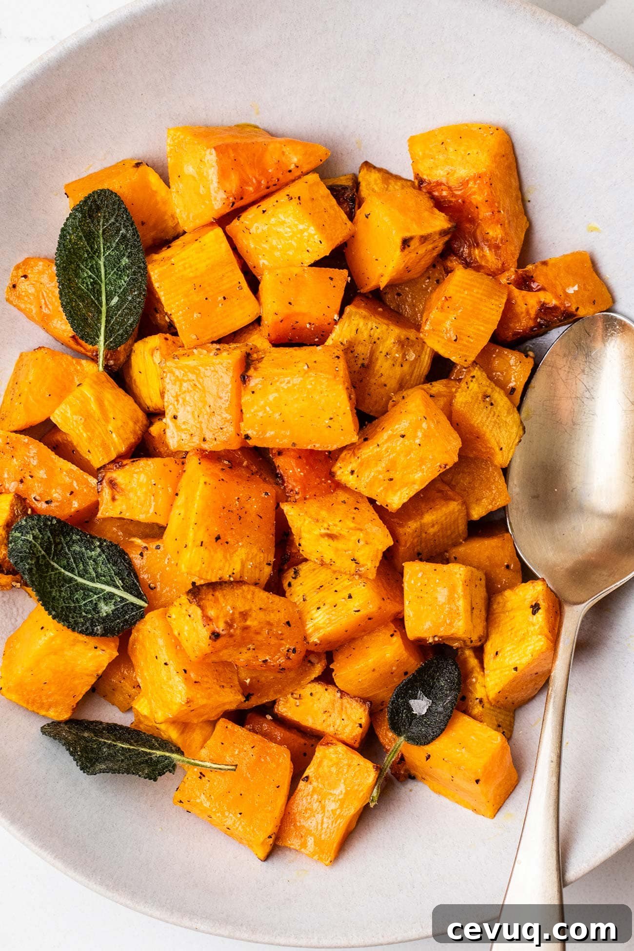 A bowl of air fryer butternut squash shown garnished with fried sage.