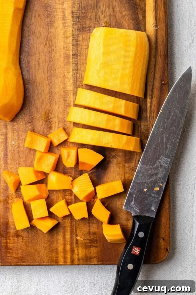 A squash cut in strips, then being cut into even sized cubes.