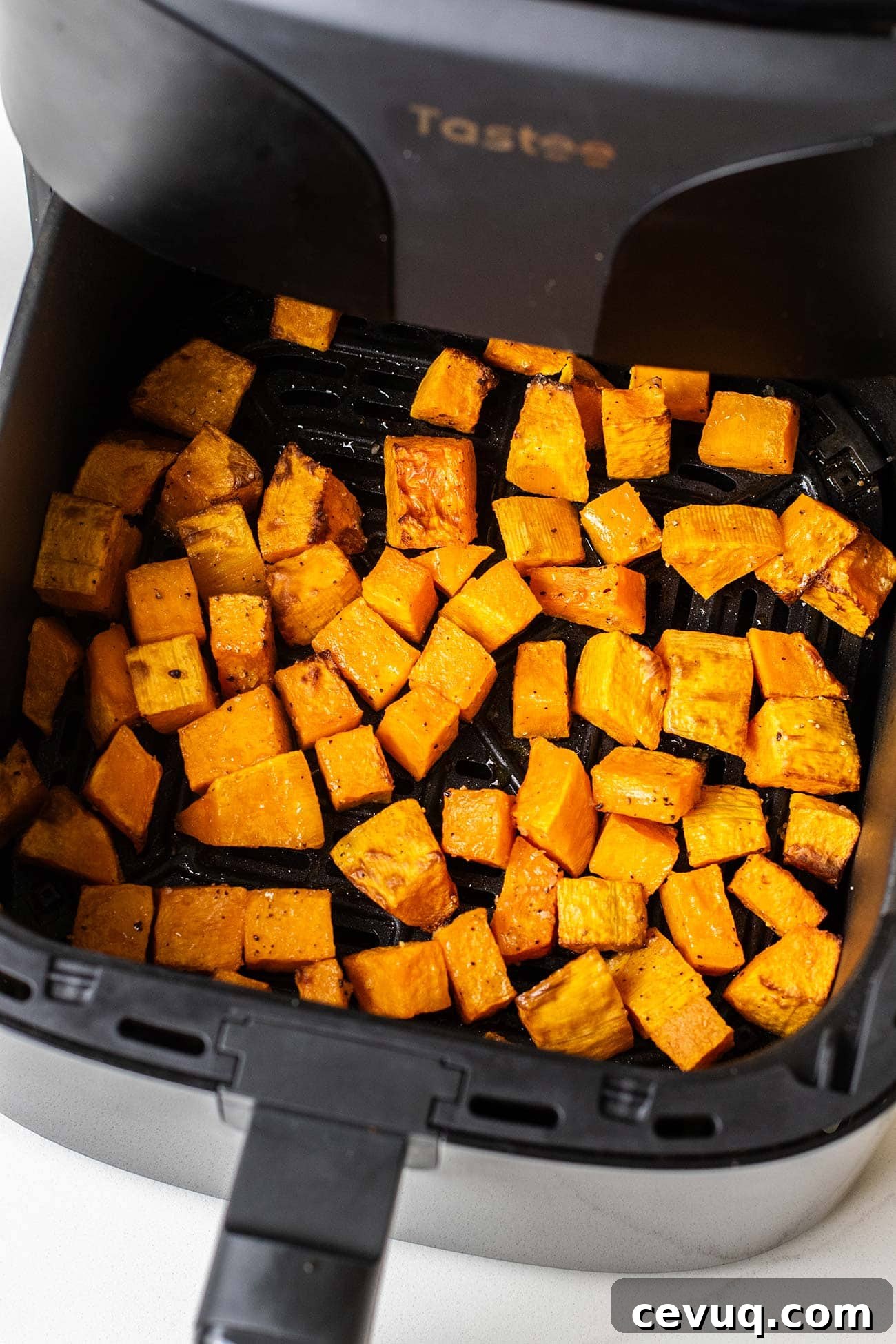 Butternut squash shown browned in an air fryer basket.