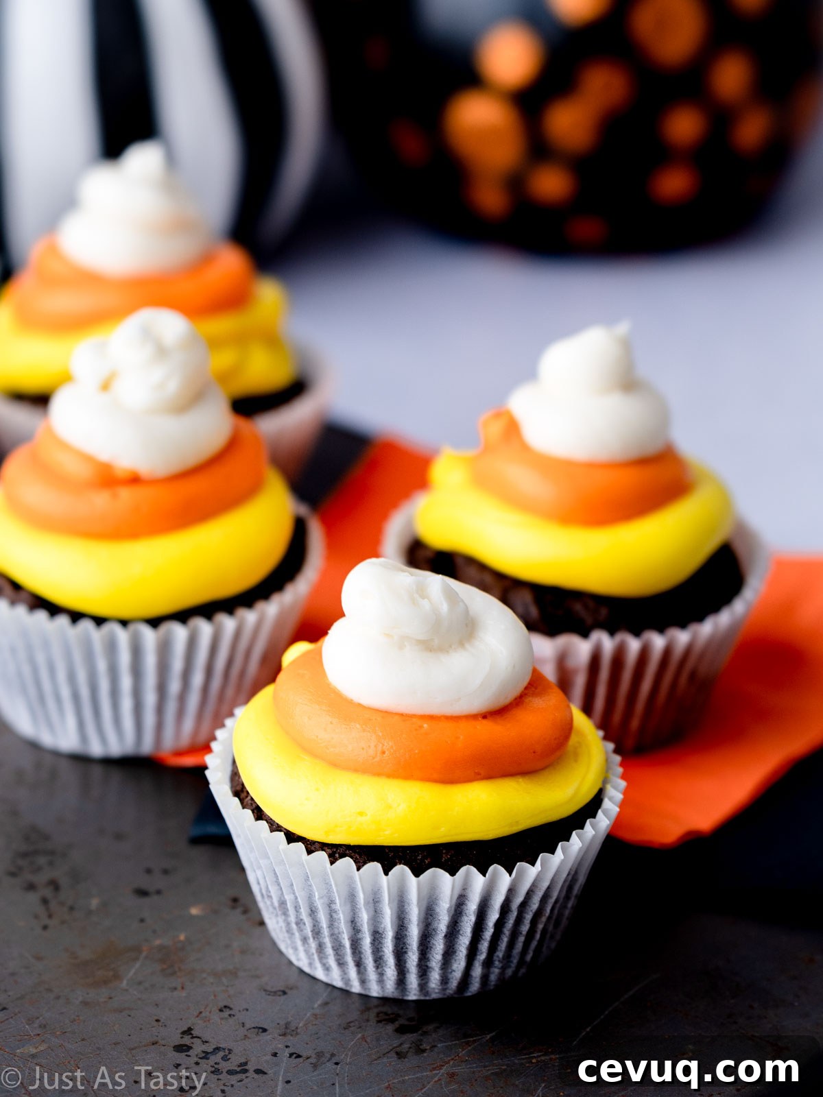 Candy Corn Cupcakes for Halloween: Festive Cupcake Recipe 2 Chocolate Halloween cupcakes topped with yellow, orange, and white frosting to look like candy corn.