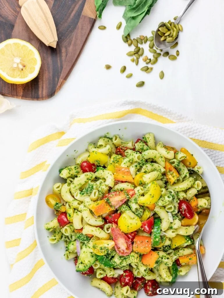 Chilled Vegan Pesto Pasta Salad Recipe for Summer Meals 2 cold vegan pesto pasta salad with tomatoes and vegetables in a white bowl with lemon
