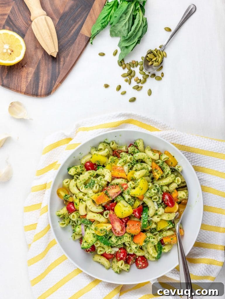 Chilled Vegan Pesto Pasta Salad Recipe for Summer Meals 6 cold vegan pesto pasta salad with tomatoes and vegetables in a white bowl with lemon