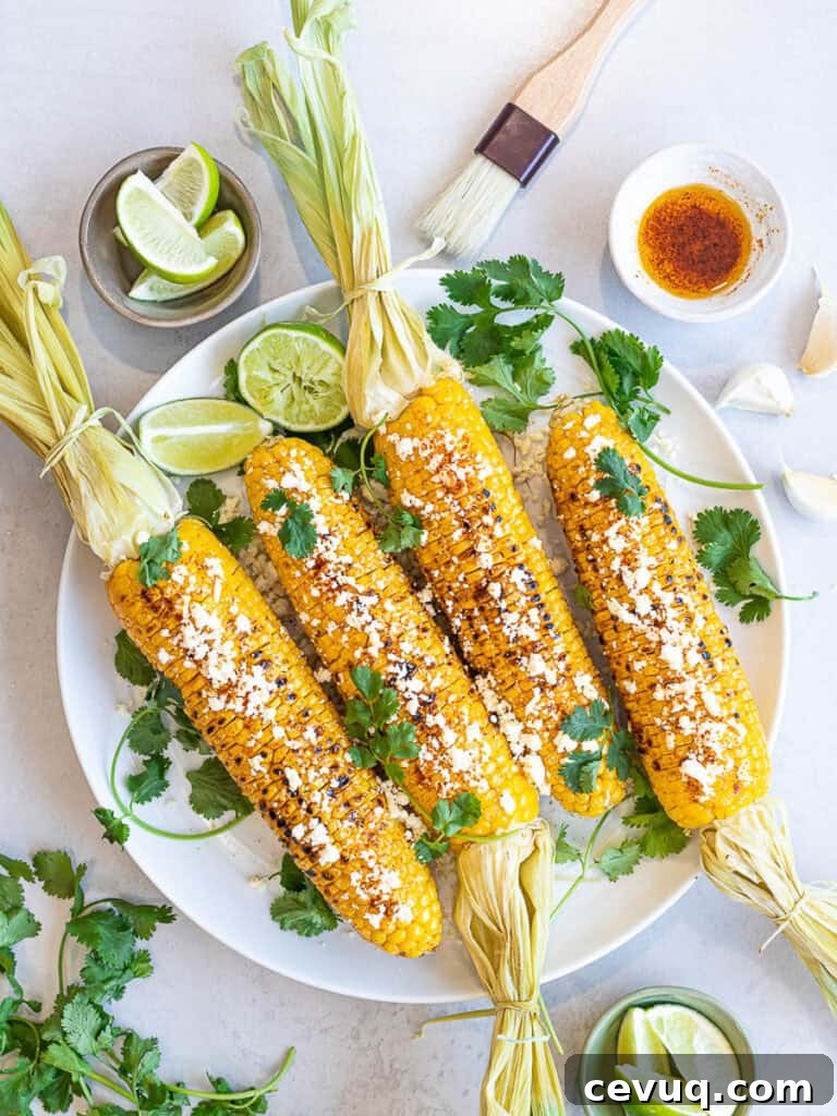 Healthy Grilled Mexican Street Corn (Elotes) with lime, cotija cheese, and cilantro on a white plate