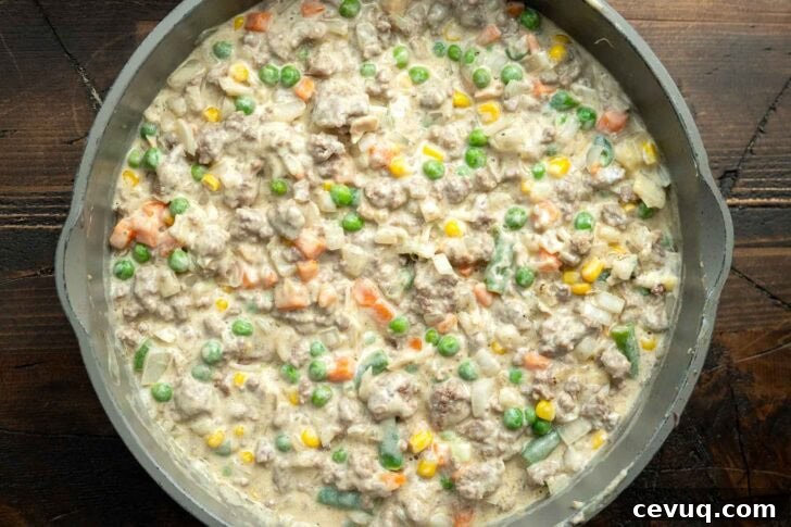 cream of soup stirred into ground beef and vegetables in a skillet