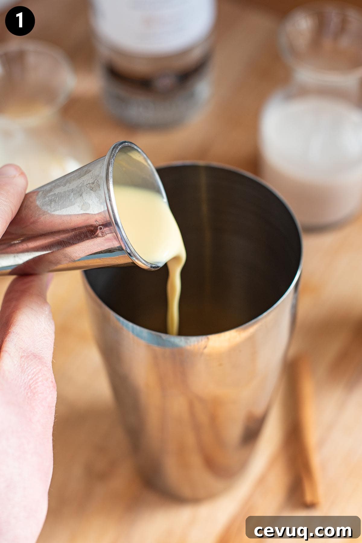 Pouring eggnog into a cocktail shaker with a cocktail jigger.