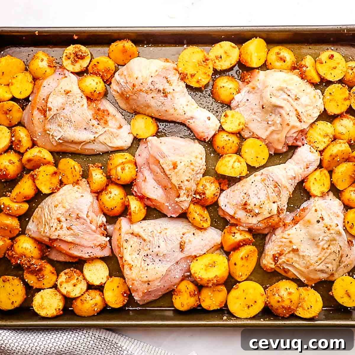 chicken and potatoes spread on a baking sheet in a single layer