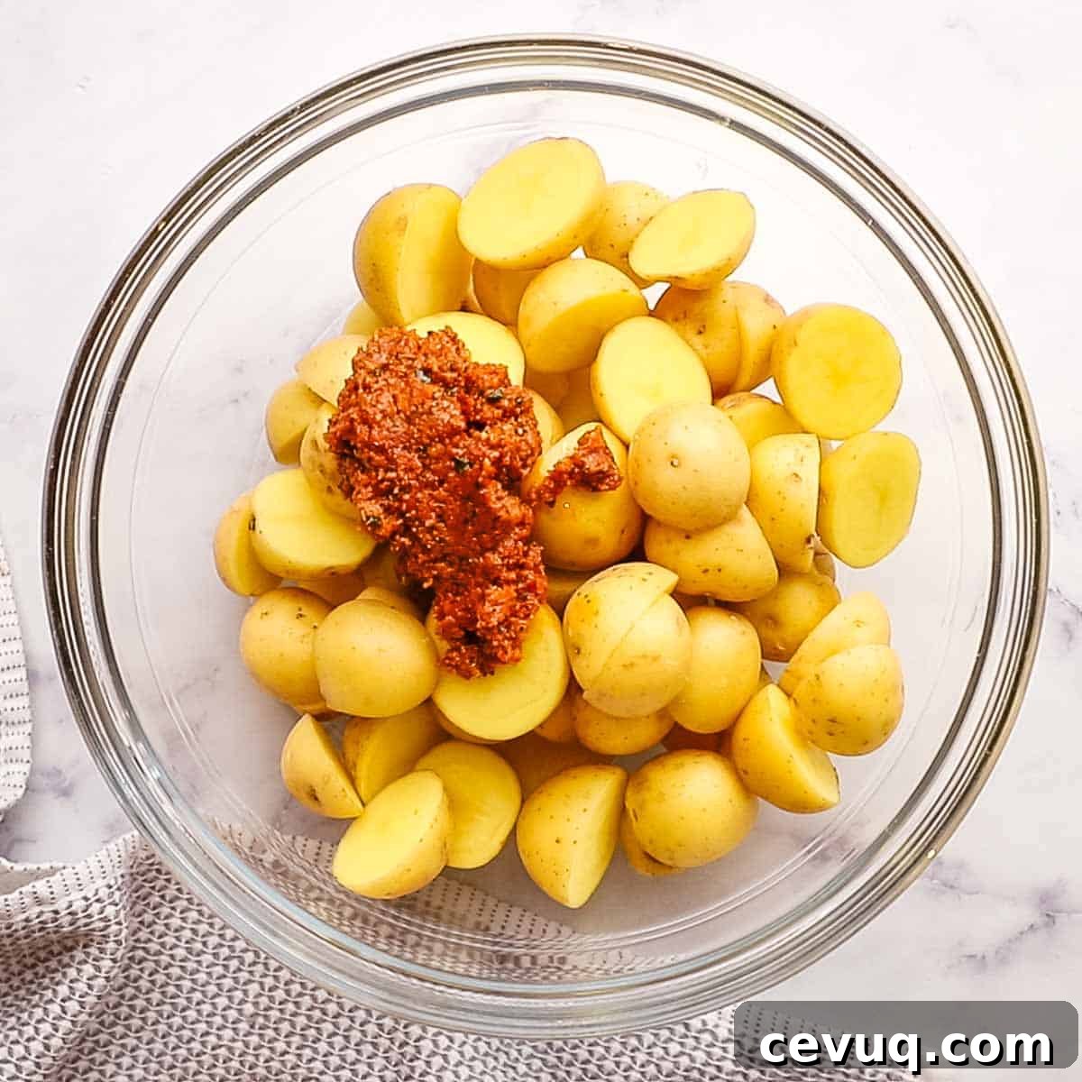 sun dried tomato pesto added to a bowl of halved baby potatoes
