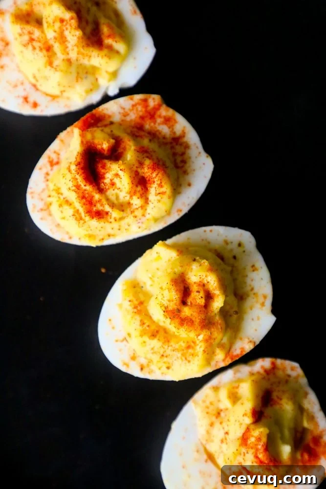 four deviled eggs with paprika sprinkled on top on a table