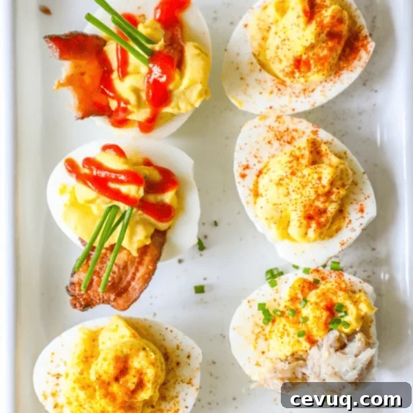 Six deviled eggs on a white tray, topped with bacon, chives, paprika, sriracha, and crab meat—these Easy Deviled Eggs Recipes are perfect for any gathering.