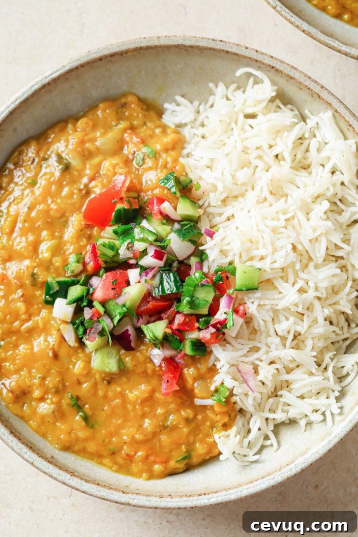 A bowl with rice and Masoor Dal topped with crunchy vegetables.