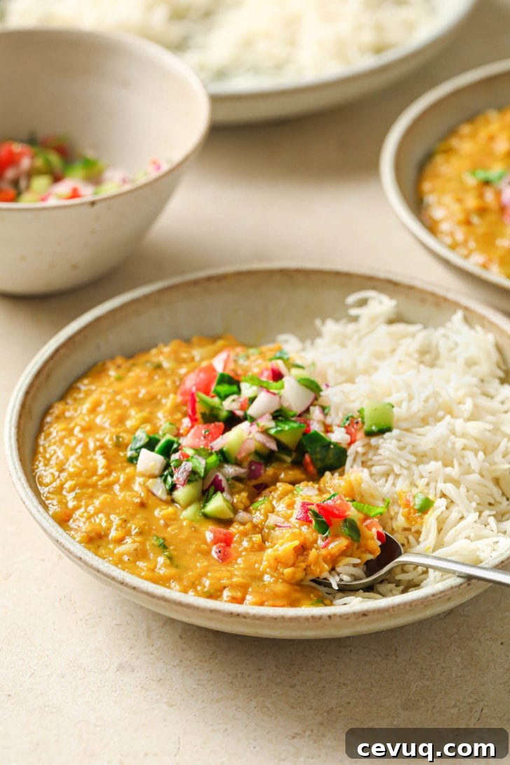 A bowl with rice and Masoor Dal topped with crunchy vegetables.