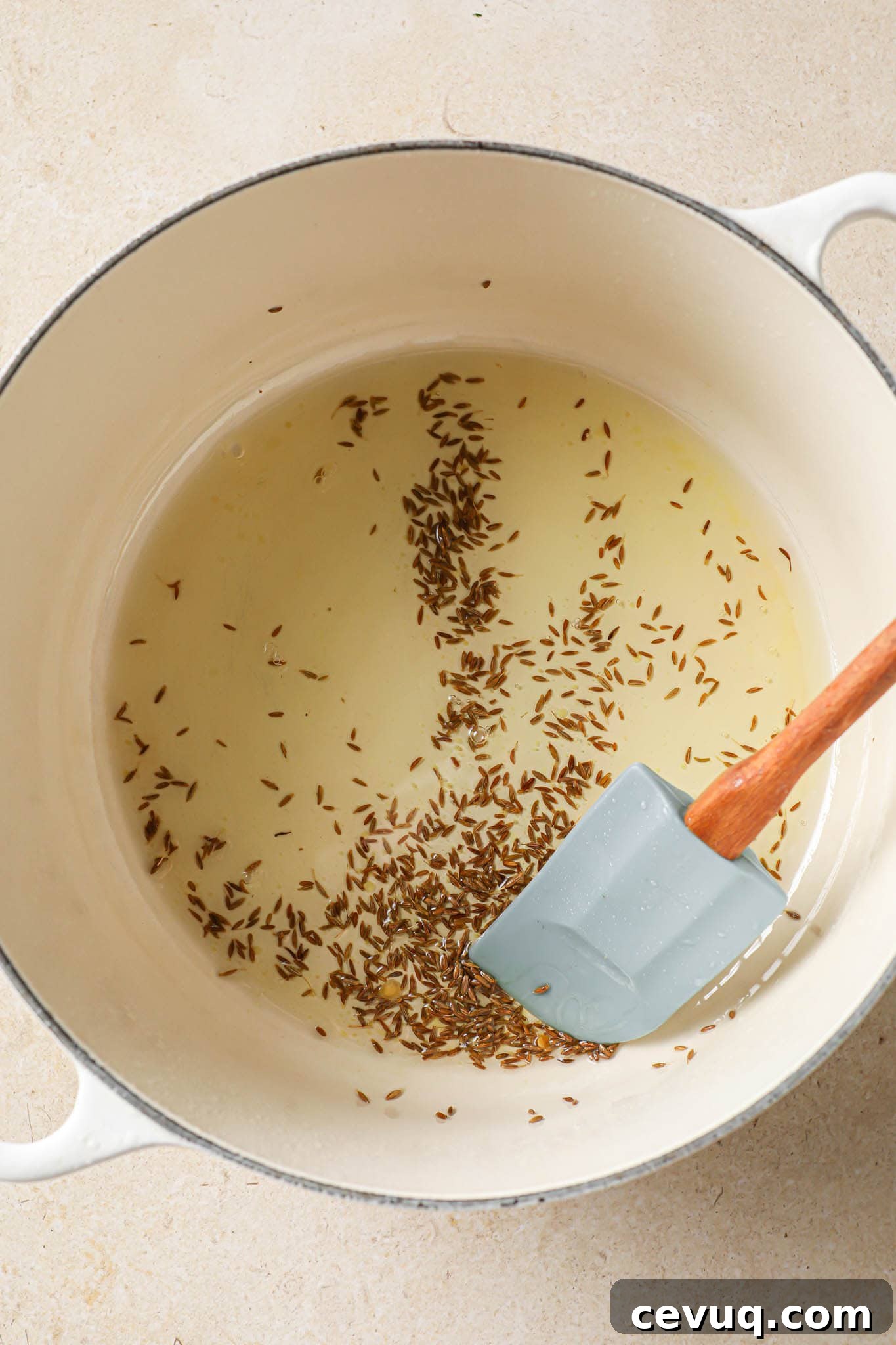 Frying cumin seeds in oil in a Dutch oven.