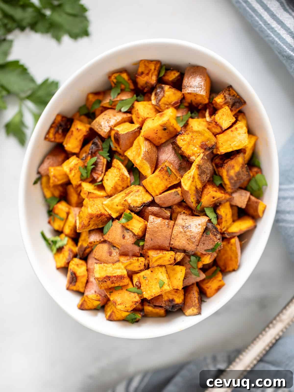 Bowl of crispy sweet potato cubes next to serving spoon. 