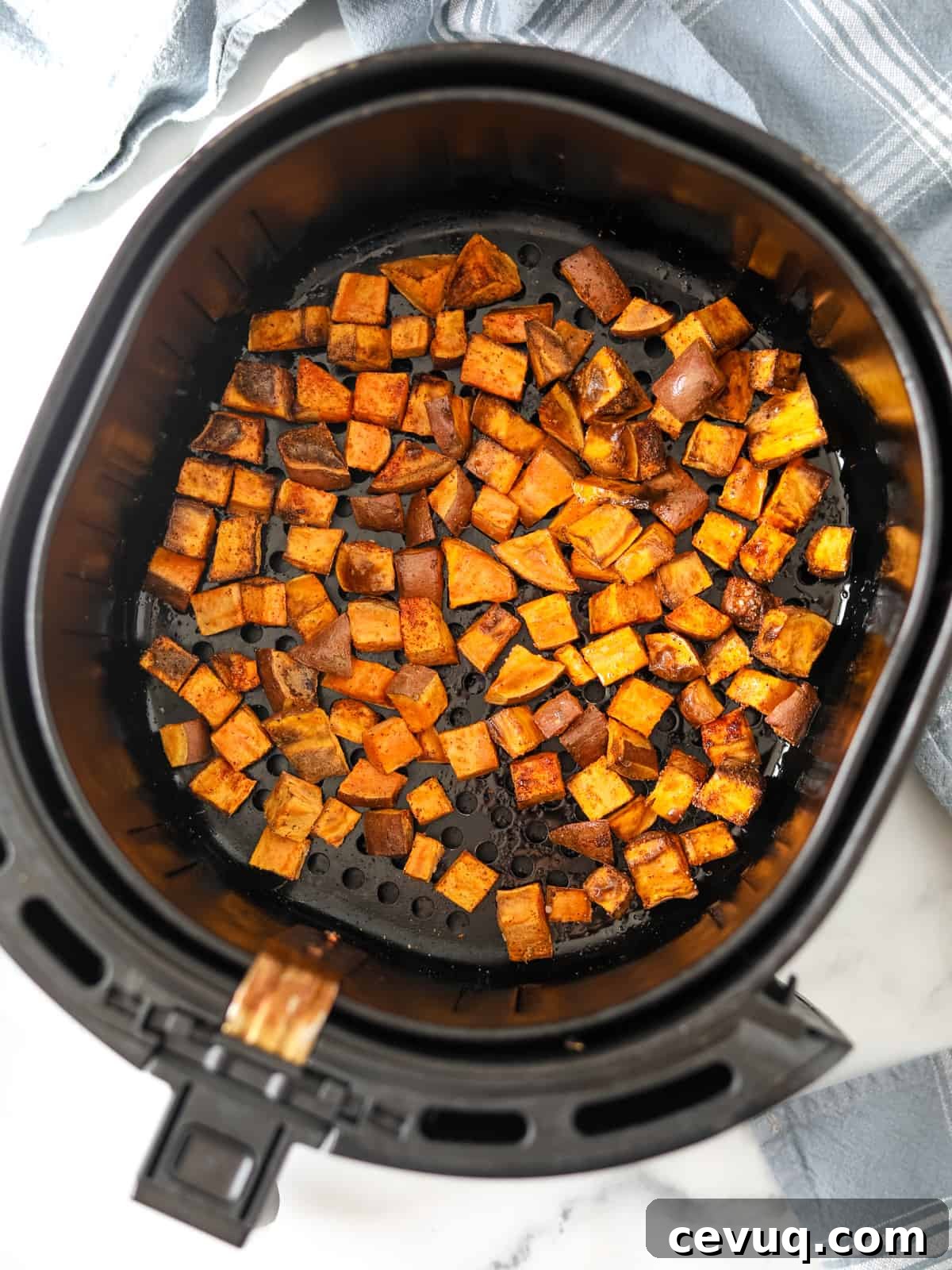 Air Fryer Basket with cubed roasted sweet potatoes. 