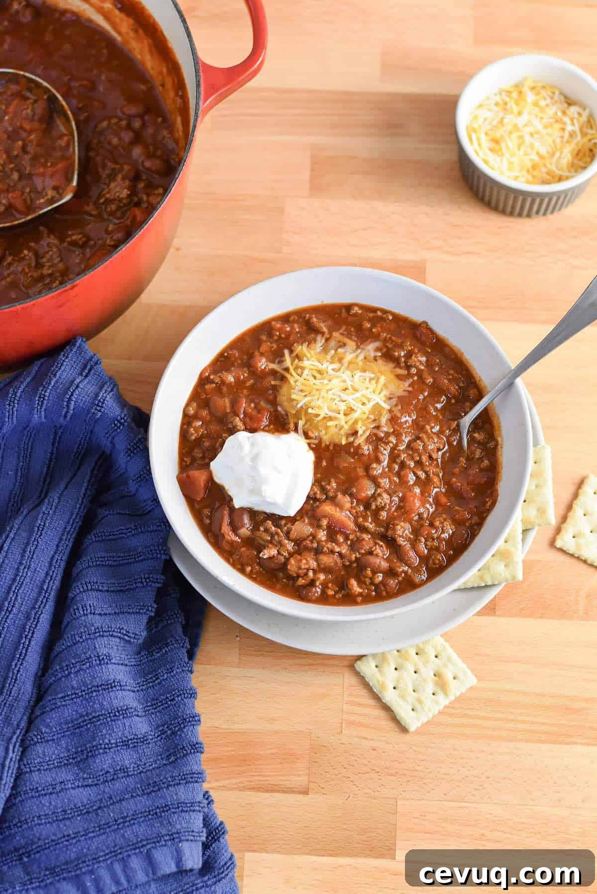 Bowl of classic chili for a crowd topped with shredded cheese and sour cream.