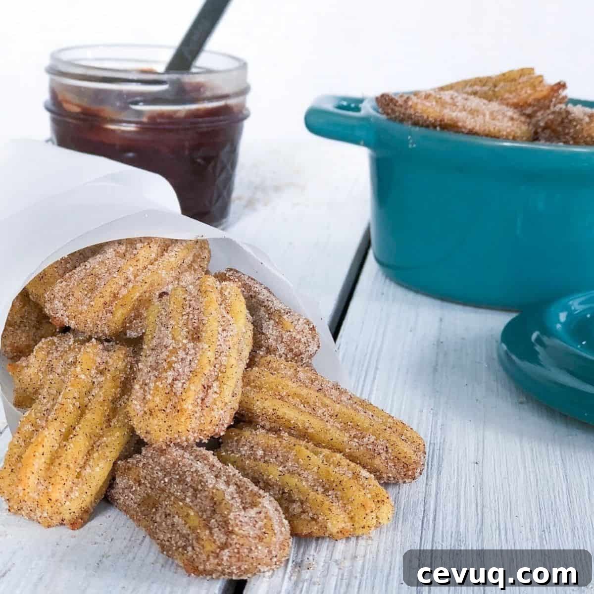 mini churros spilled onto a table with sauce behind it.