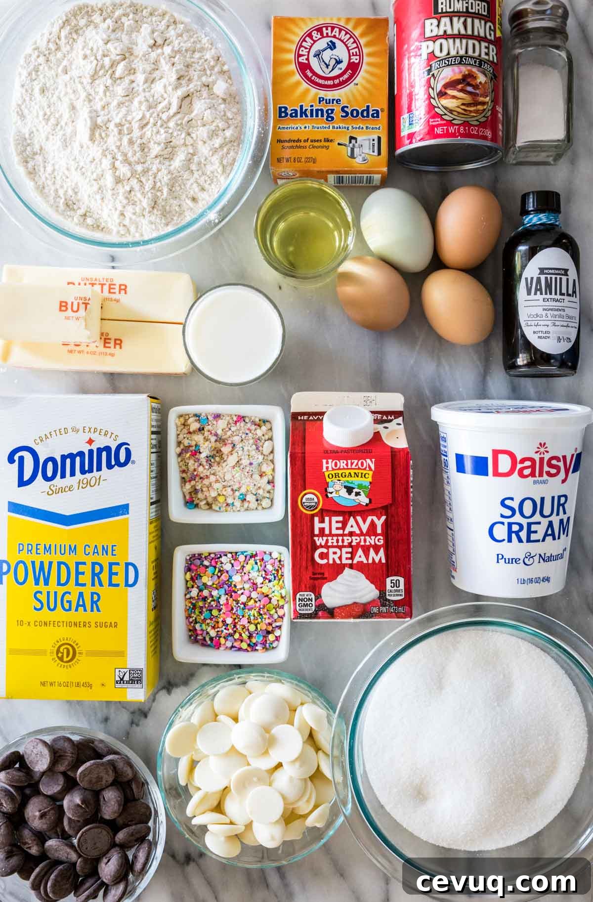 Overhead view of ingredients including flour, butter, powdered sugar, sprinkles, sour cream, and more.