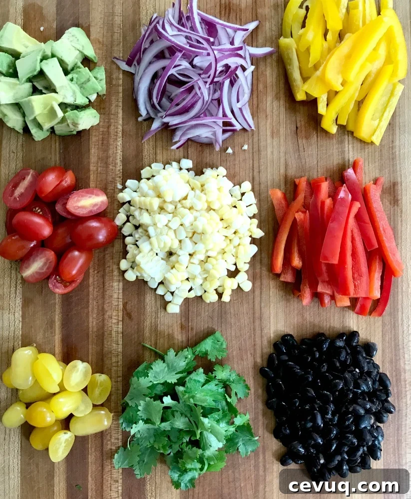 colorful chopped veggies: avocado, tomatoes, onions, bell peppers, cilantro, corn, black beans