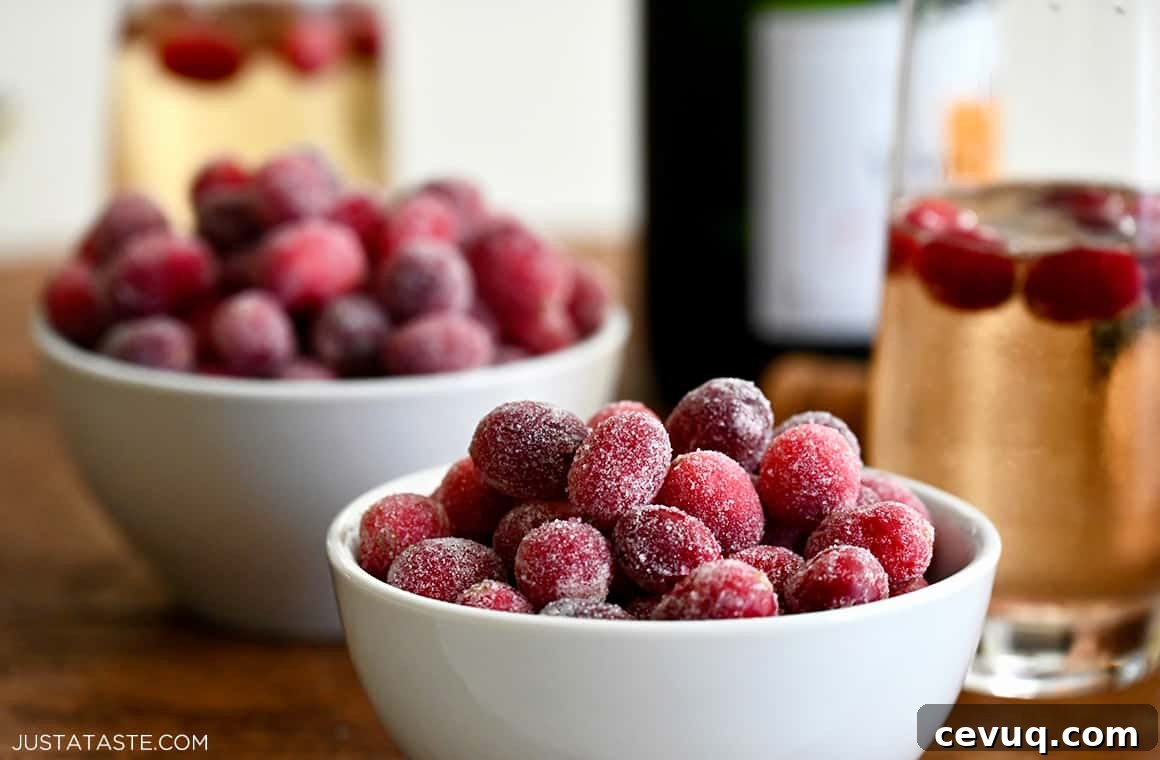 Festive candied cranberries piled high in a small bowl next to a glass of sparkling wine 