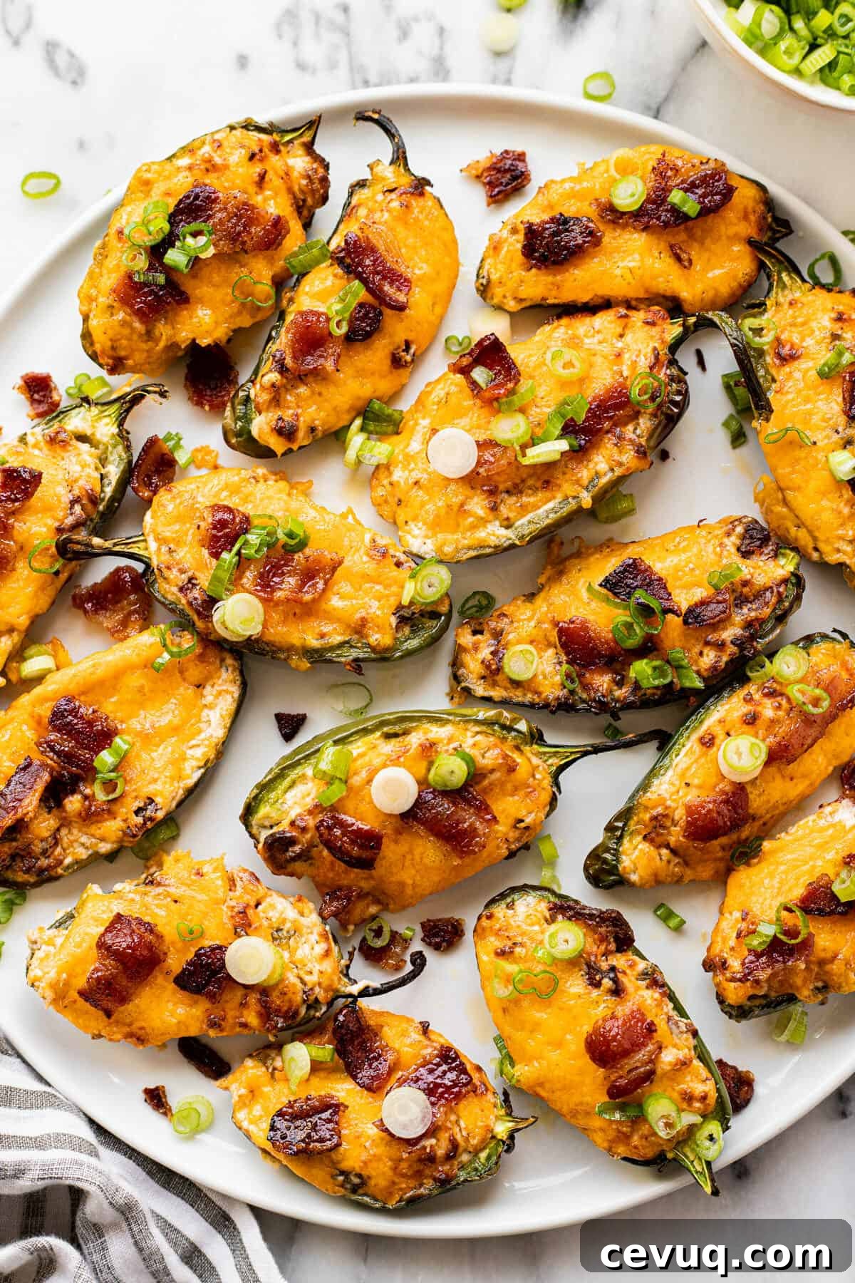 White plate filled with homemade air fryer jalapeno poppers garnished with sliced green onion.