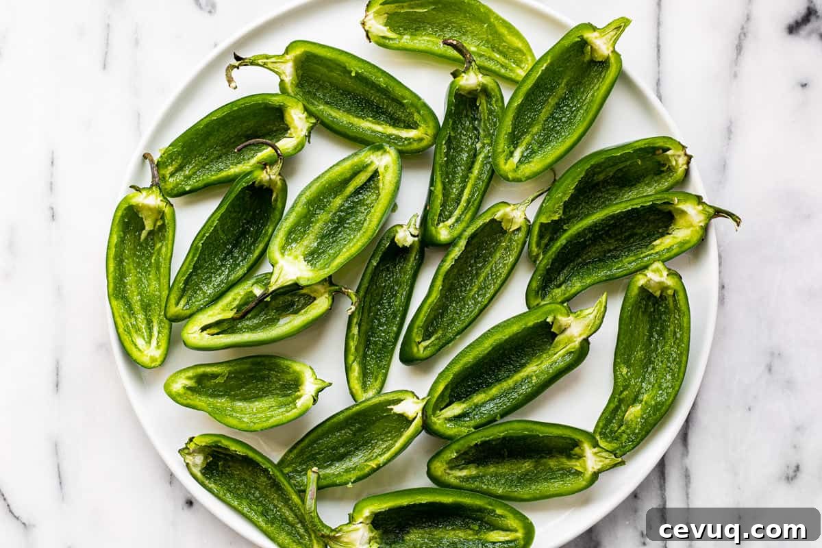 White plate with sliced jalapenos with the ribs and seeds removed.