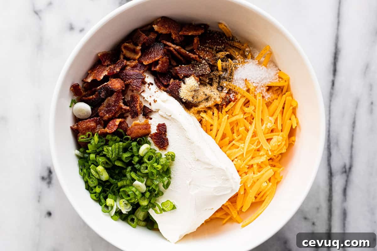 White bowl filled with cream cheese, bacon, cheddar, green onions, and spices.