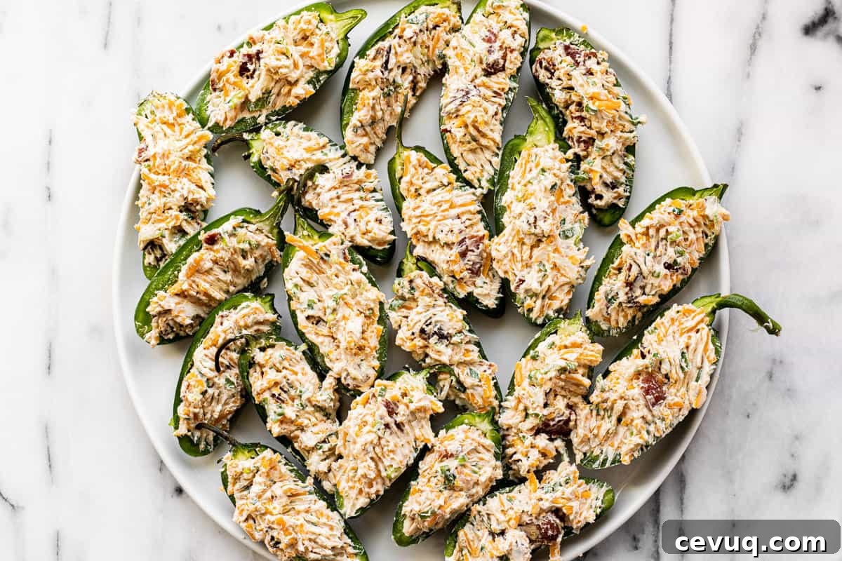 Freshly stuffed jalapeno poppers on a white plate.