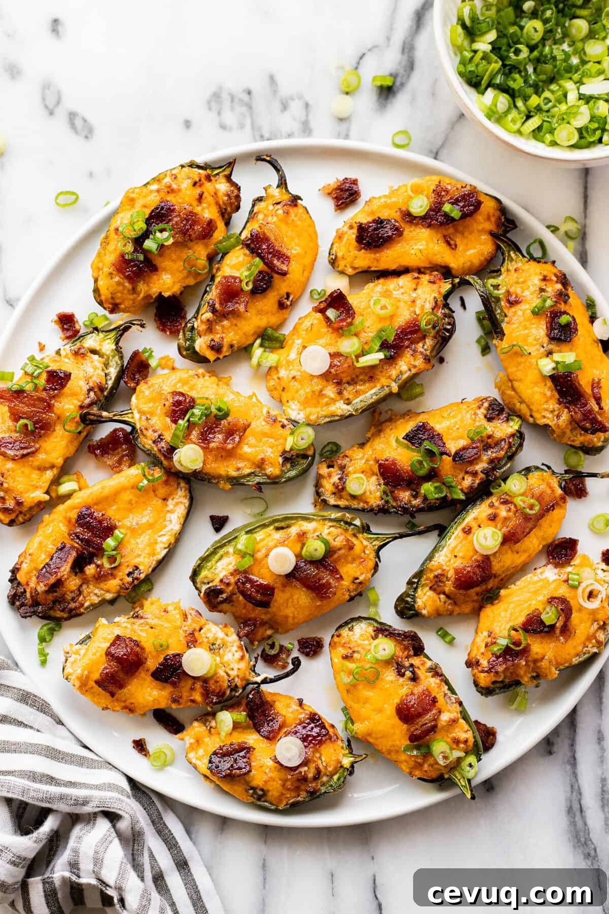 White plate filled with homemade air fryer jalapeno poppers garnished with sliced green onion.