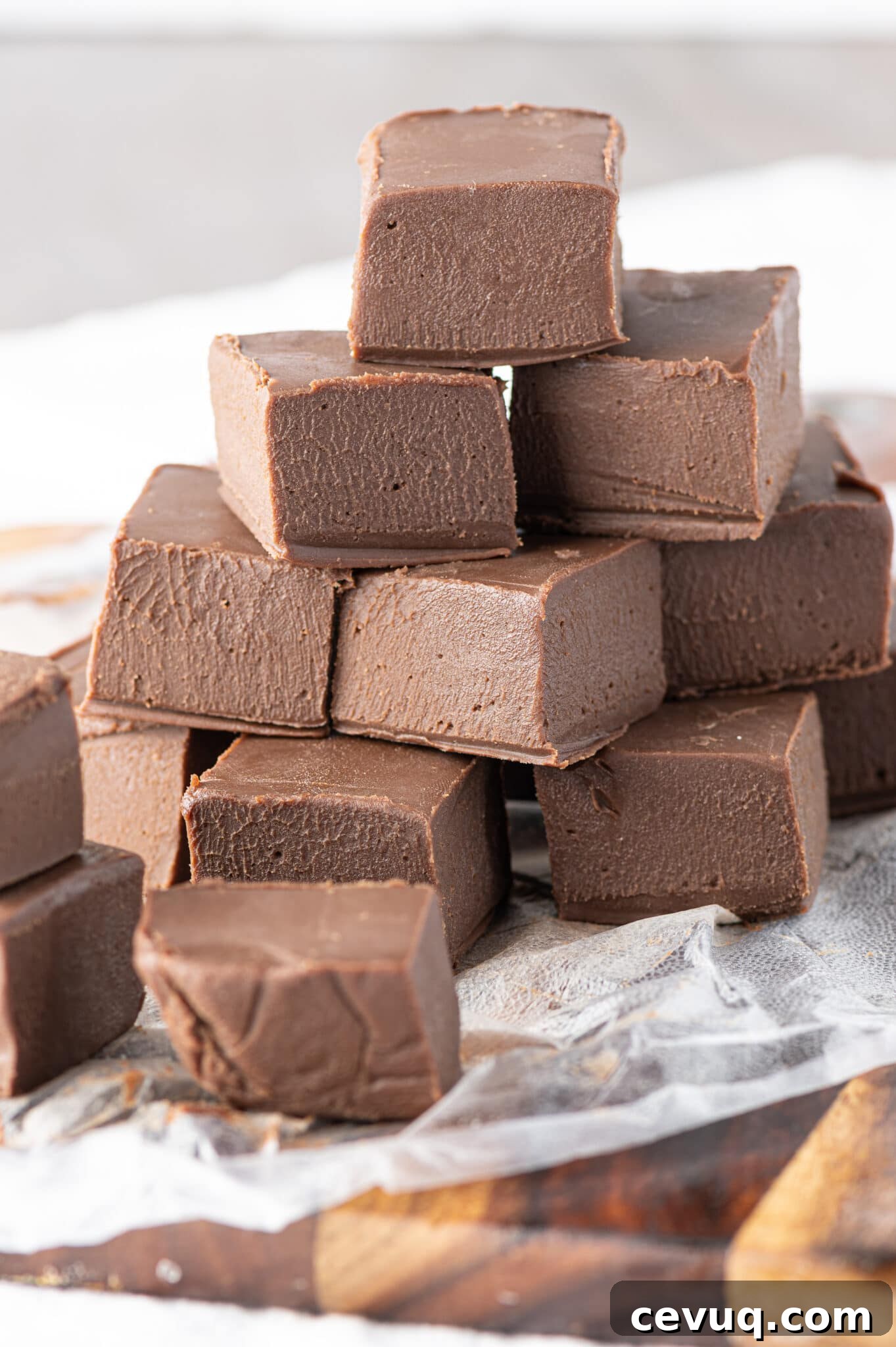 A stack of keto chocolate fudge made from this recipe on a rustic wooden cutting board. 