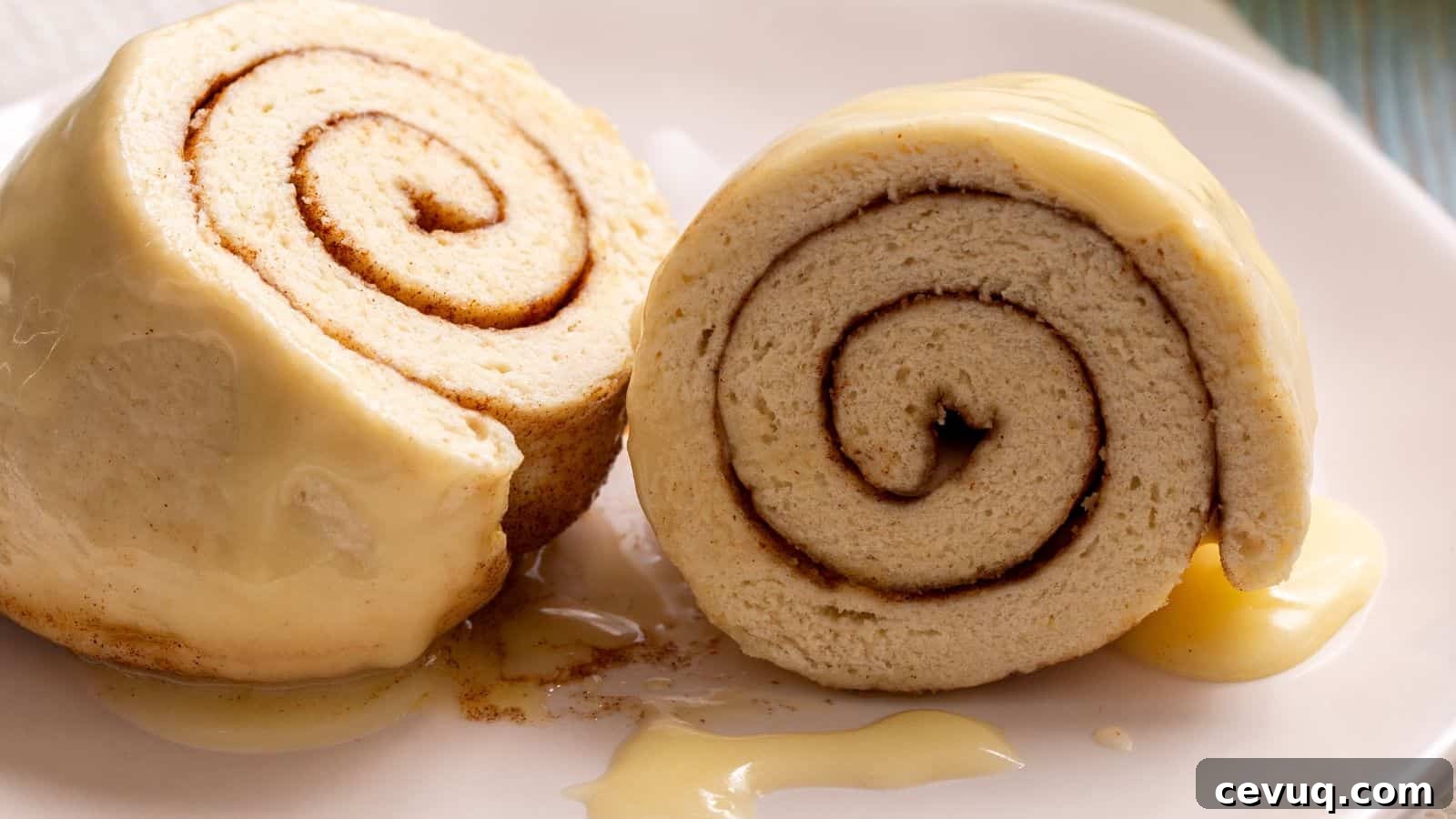 Two slices of cinnamon roll cake with vanilla glaze on a white plate.