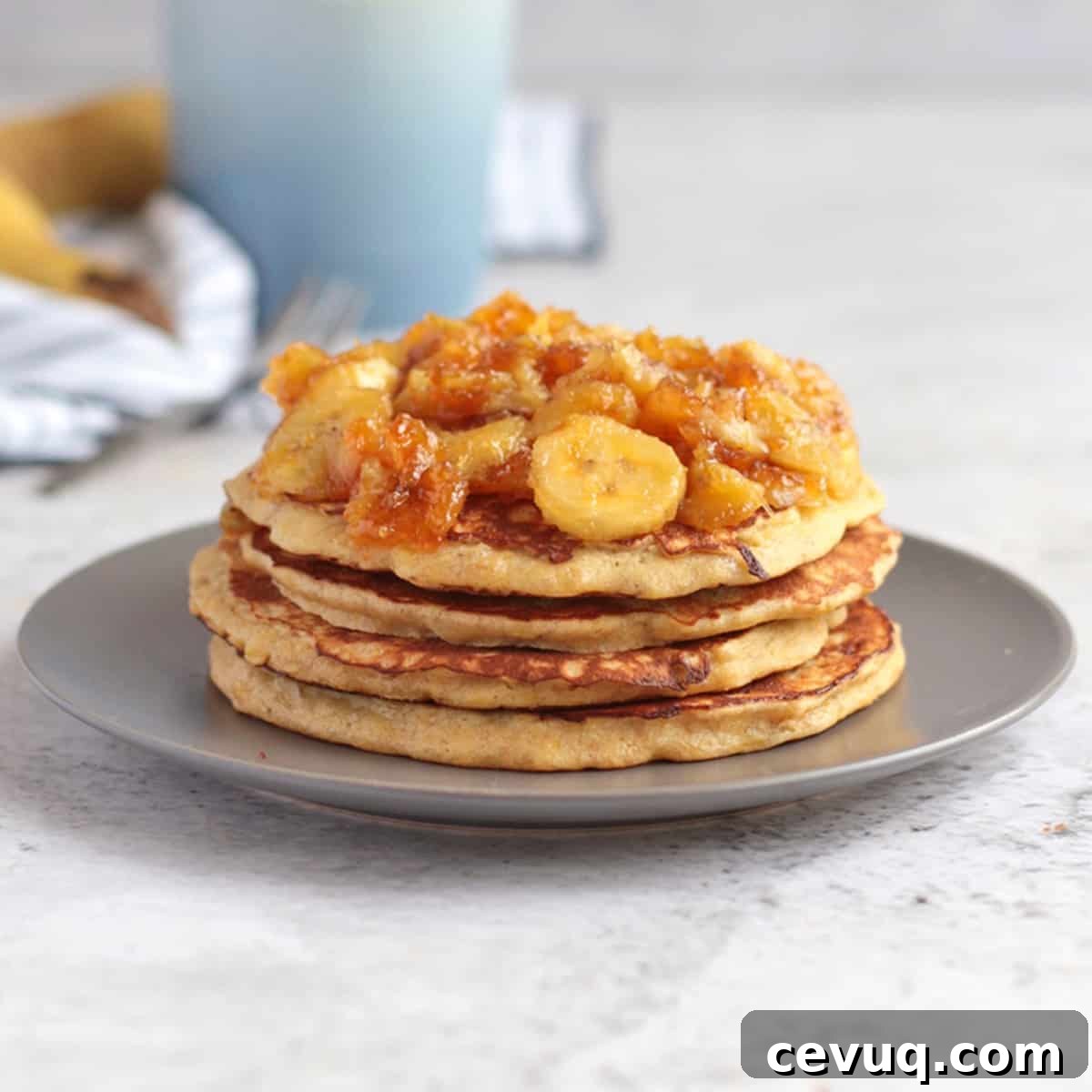 Banana Pancakes stacked on a grey plate and topped with honey caramelised bananas.