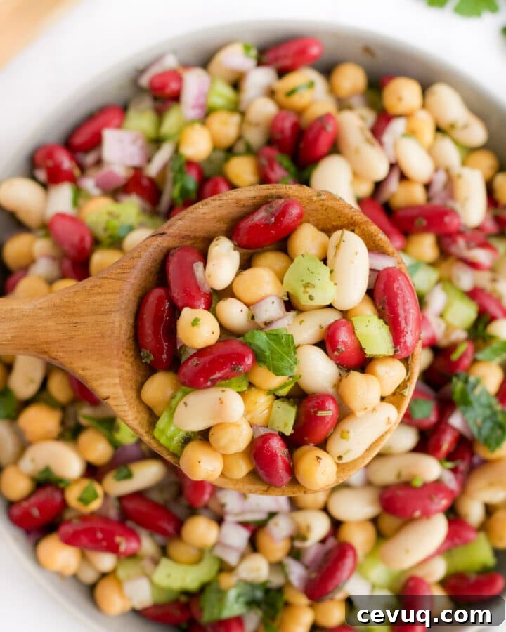three bean salad being scooped by a wooden spoon