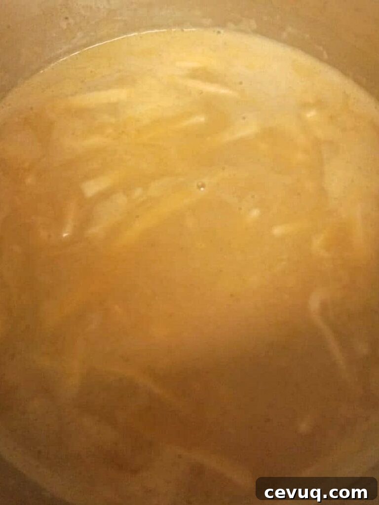 a large pot of browned butter with broth and noodles.