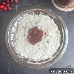 Traditional cranberry pickle served on a silver plate with spicy chutney.