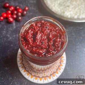 Vibrant cranberry pickle in a glass jar, perfect for traditional South Indian cuisine.