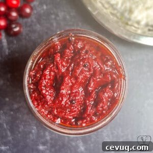 Spicy homemade cranberry oorugai in glass jar, traditional Indian pickle.