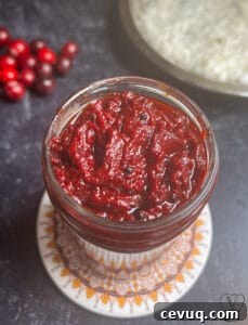 Vibrant cranberry pickle in a glass jar, perfect for traditional Indian cuisine.