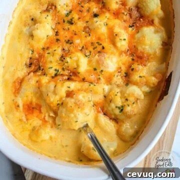 Creamy Cauliflower Mac & Cheese Casserole 9 Cauliflower Mac and cheese in a white casserole dish with a serving spoon.