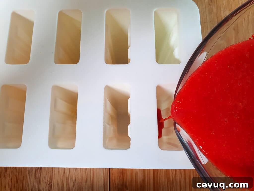 Filing popsicle molds with strawberry mix.