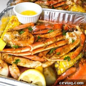 Seafood bake with lobster, crab, shrimp and seasonings in a pan with lemon and butter on the side.
