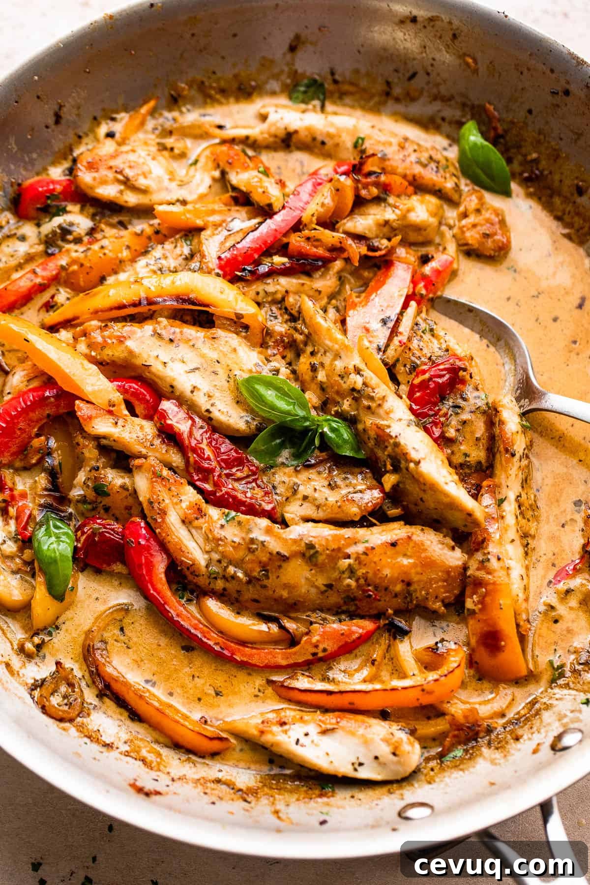 overhead shot of a skillet with creamy pesto chicken strips, peppers, and cream sauce