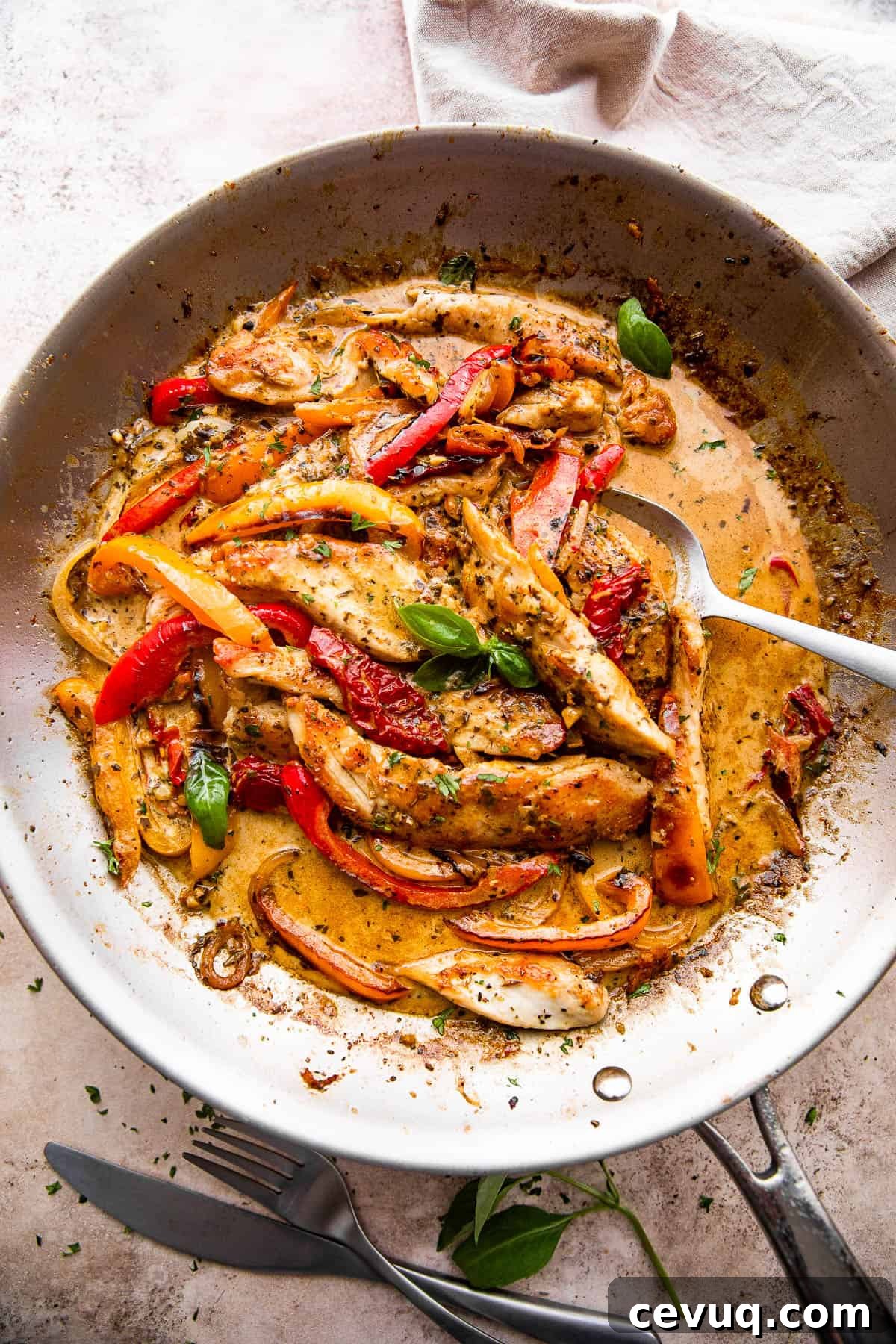 overhead shot of a skillet with creamy pesto chicken strips, peppers, and cream sauce