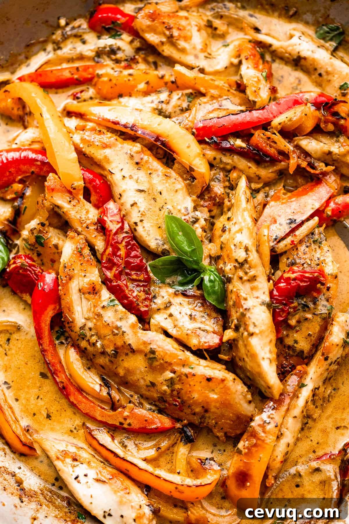 close up shot of chicken strips, bell pepper strips, and creamy pesto sauce