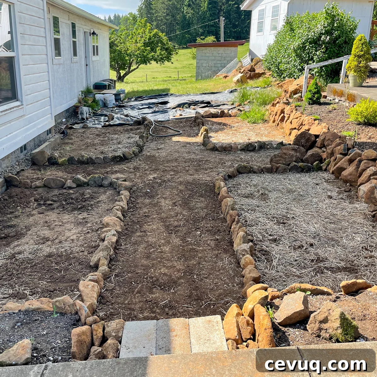 rock wall raised beds and four rock outlined beds for future flowers.
