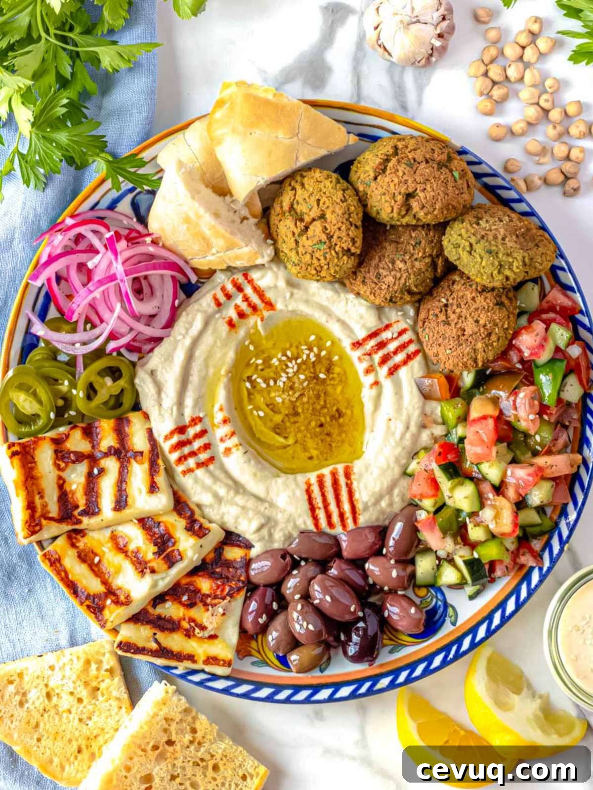 Meze platter with falafel, hummus, olives, halloumi, and pita bread.