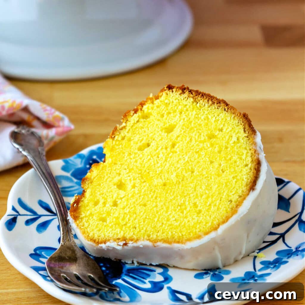 Lemon Pound Cake Recipe for True Lemon Lovers 3 A bright yellow slice of lemon pound cake on a blue-patterned plate.