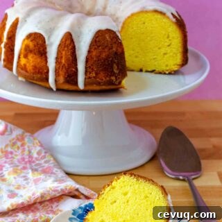 Lemon Pound Cake Recipe for True Lemon Lovers 9 A lemon Bundt cake on a white cake stand with a slice of the cake on a plate.